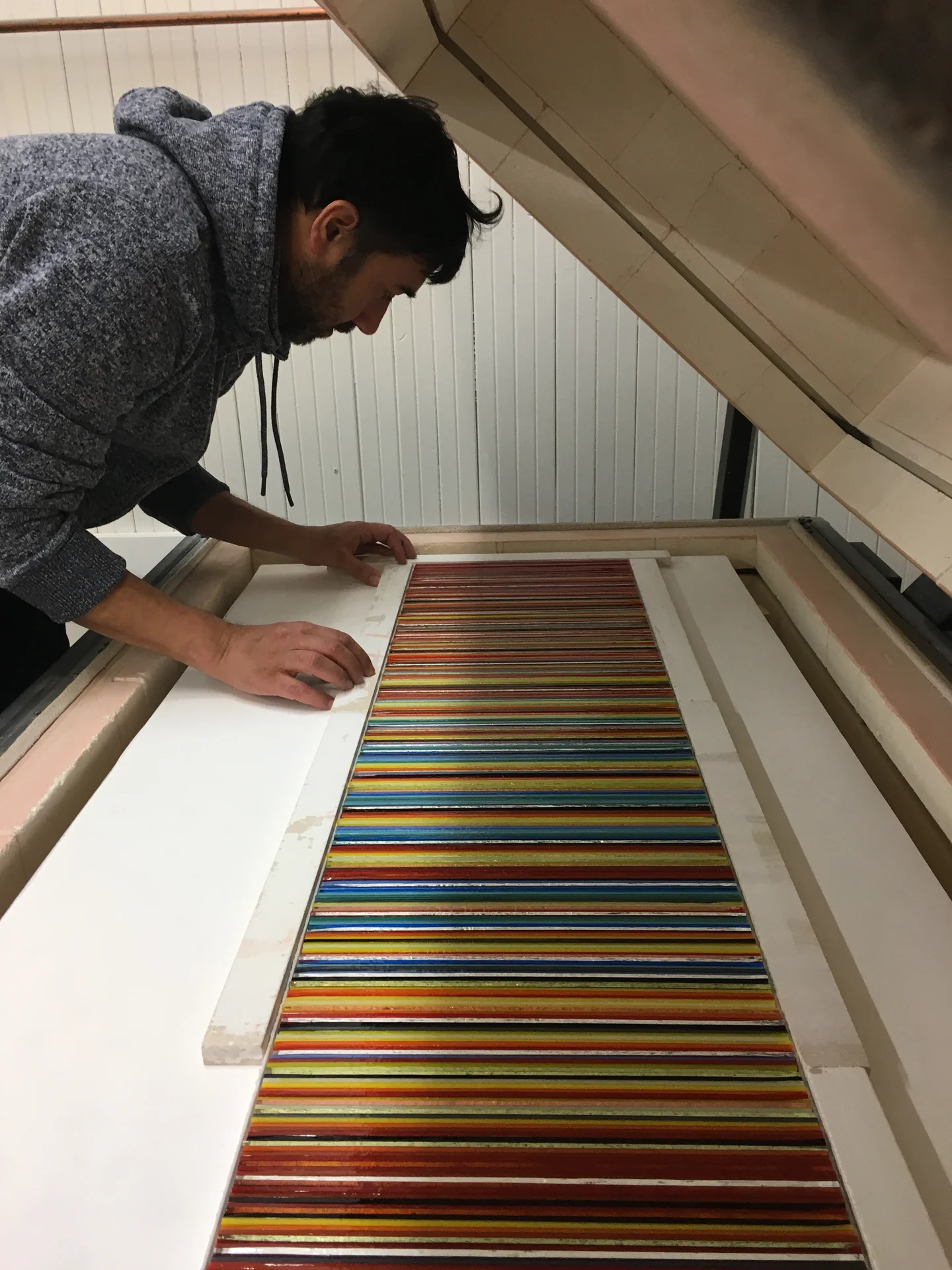 Romy Randev leaning over a colourful striped glass panel