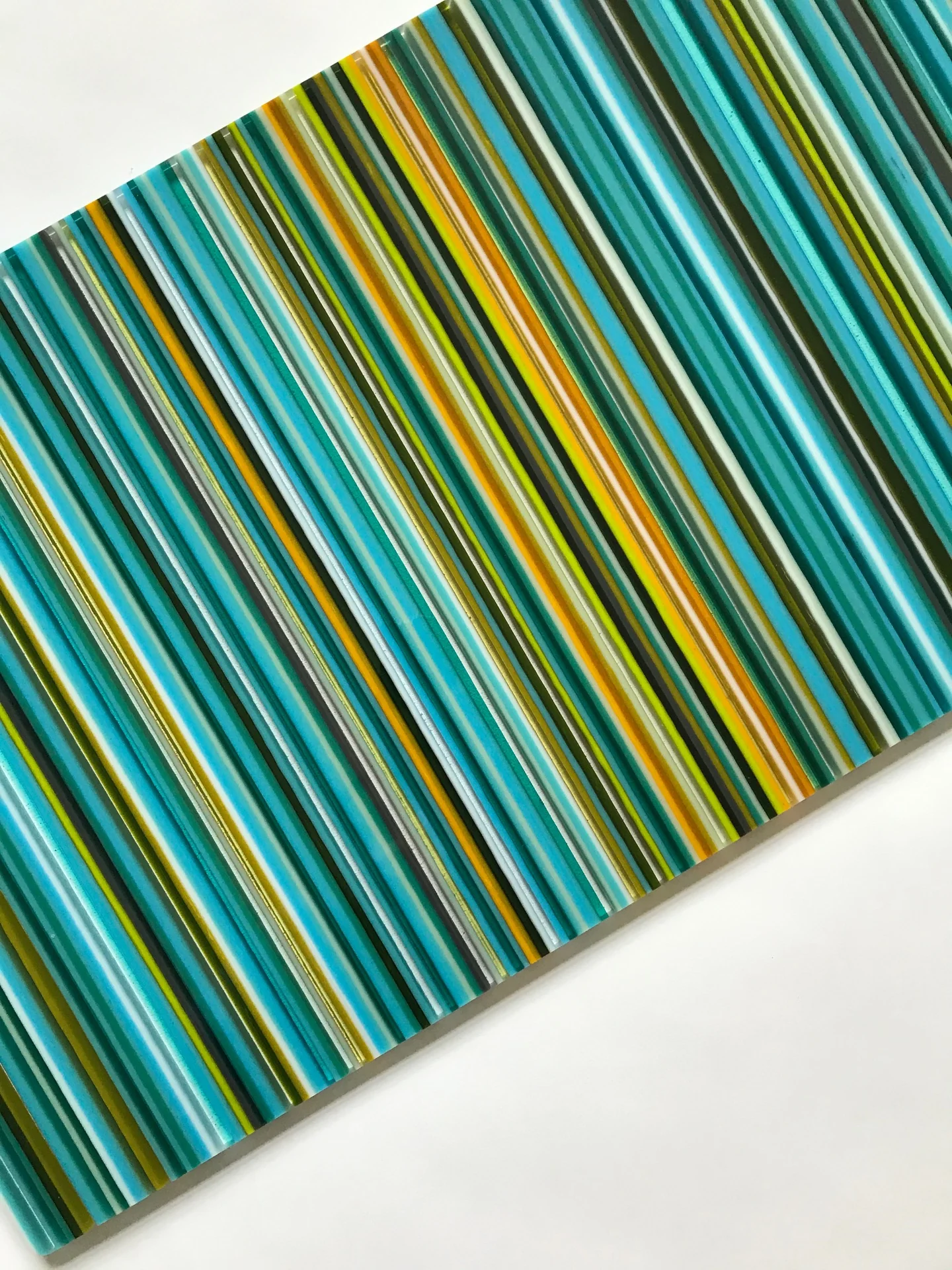 Close view of diagonal turquoise, yellow and orange glass stripes