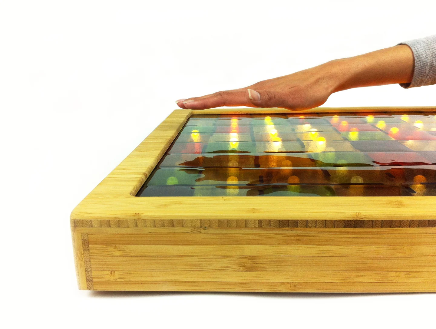 A hand hovering above a luminous tiled surface in a light wood frame